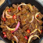 Plate of spicy stir-fried beef with onions and chilies