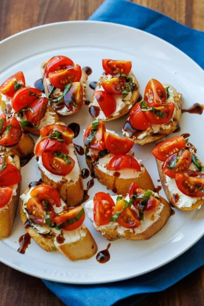 Delicious Tomato Goat Cheese Crostini topped with fresh herbs and tomatoes
