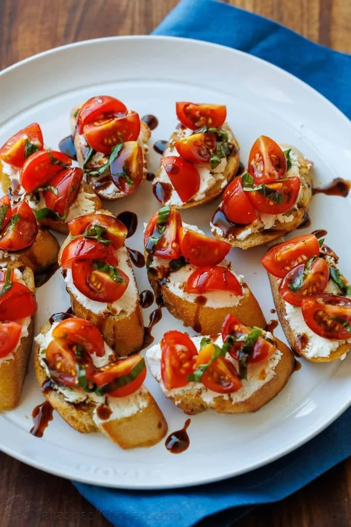 Delicious Tomato Goat Cheese Crostini topped with fresh herbs and tomatoes